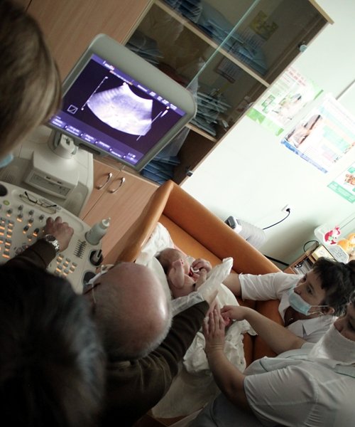 Пыков Михаил Иванович проводит ультразвуковую диагностику почек у новорожденной девочки
