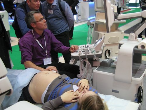 Исследование беременной на ультразвуковом сканере Accuvix-XG, за показаниями прибора наблюдают посетители выставки.
